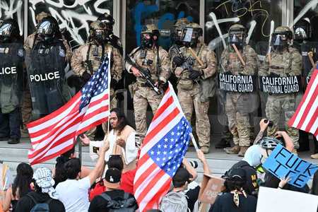 １０日、米ロサンゼルス市内の連邦ビルを警備するカリフォルニア州兵と警察官（ＡＦＰ時事）