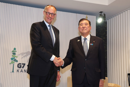 首脳会談を前に握手する石破茂首相(右)とドイツのメルツ首相=16日、カナダ・カナナスキス