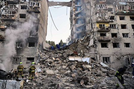 17日、キーウで、ロシアのミサイル攻撃を受けて崩壊した集合住宅で捜索活動を行う救助隊員(AFP時事)