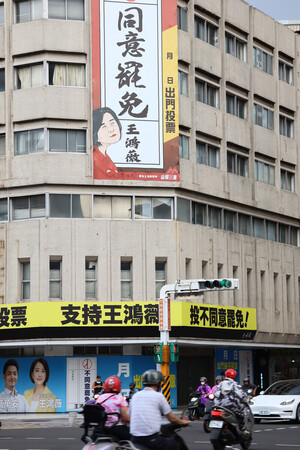 20日、台北市で、台湾の国民党立法委員(国会議員)のリコール(解職請求)投票に向け、「罷免同意」を求める看板と罷免への不同意を訴える横断幕が同時に掲げられたビル