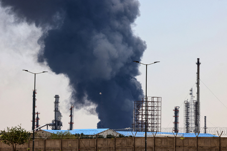 イスラエルの攻撃を受け、煙と炎を上げるイランの石油精製施設=15日、テヘラン南部(AFP時事)