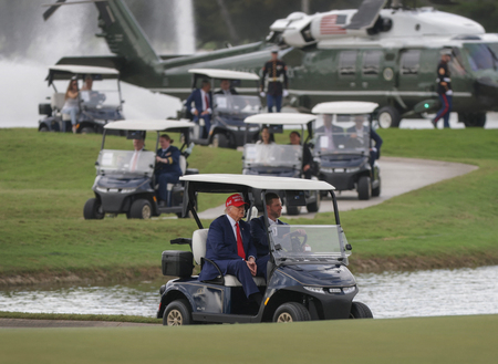 息子のエリック氏とともに、ゴルフカートに乗るトランプ米大統領=4月3日、フロリダ州ドラル(AFP時事)