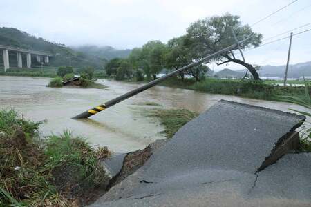 豪雨で損壊した道路と倒れた電柱＝１７日、韓国・忠清南道（ＥＰＡ時事）