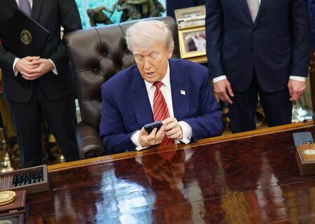 ホワイトハウスの執務室で携帯電話をチェックするトランプ米大統領=5月23日、ワシントン(EPA時事)