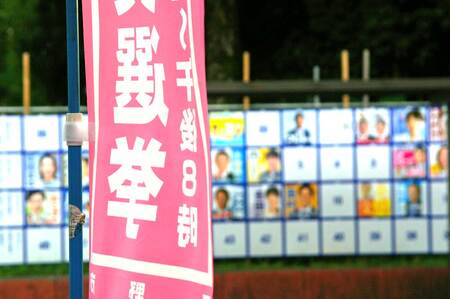 参院選の投票日を知らせる旗（手前）とポスター掲示板＝１７日、東京都日野市