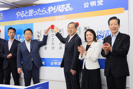 当選確実の候補者名に花を付ける公明党の斉藤鉄夫代表（中央）ら。右端は山口那津男元代表＝２０日午後、東京都新宿区