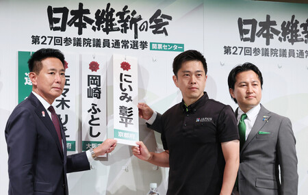 当選確実となった候補者名の前で、撮影に応じる日本維新の会の（左から）前原誠司共同代表、吉村洋文代表、岩谷良平幹事長＝２０日午後、大阪市北区