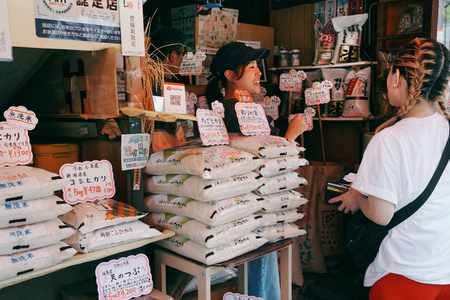 接客する精米店の店員(左)=18日、東京都内(AFP時事)