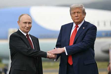 15日、米アラスカ州アンカレジのエルメンドルフ・リチャードソン米軍基地に到着し、握手を交わすトランプ米大統領(右)とロシアのプーチン大統領(AFP時事)