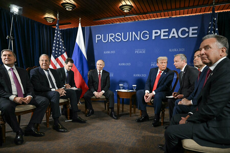 15日、米アラスカ州アンカレジで会談に臨むロシア代表団(左)と米国代表団(AFP時事)