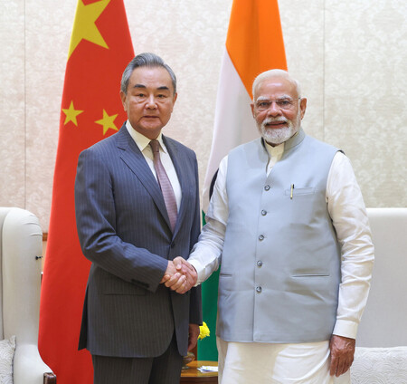 １９日、インド・ニューデリーでの会談に際し、握手する中国の王毅共産党政治局員兼外相（左）とモディ首相（インド政府提供・時事）