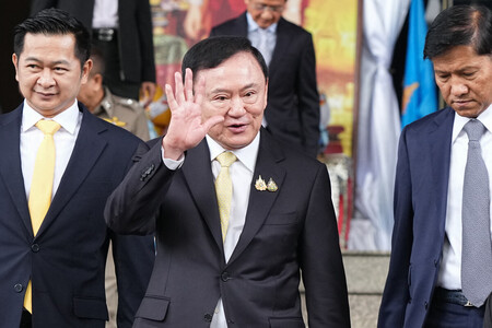 ２２日、バンコクの刑事裁判所を後にするタイのタクシン元首相（中央）（ＡＦＰ時事）
