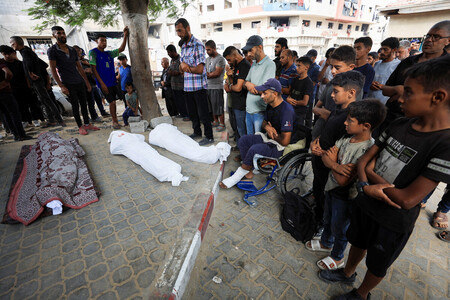 21日、パレスチナ自治区ガザの中心都市ガザ市で、イスラエルの攻撃により死亡した住民を悼む人々(ロイター時事)