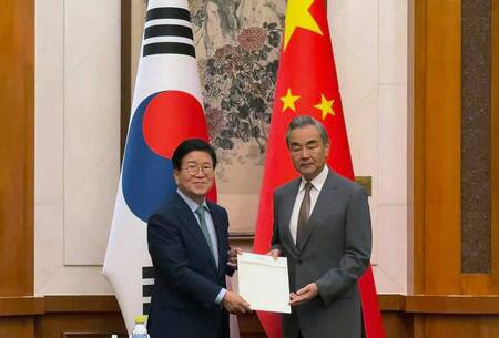 24日、北京で面会する韓国の朴炳錫元国会議長(左)と中国の王毅共産党政治局員兼外相(EPA時事)