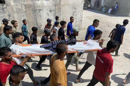 ２５日、パレスチナ自治区ガザ南部ハンユニスで、イスラエル軍のナセル病院攻撃により死亡した報道関係者の遺体を運ぶ人々（ＡＦＰ時事）