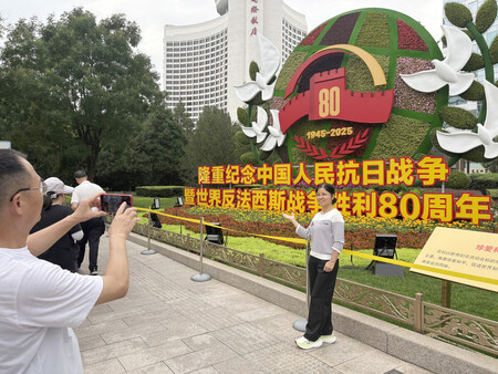 「戦勝80年」を記念して設置された花壇で写真を撮る人々=8月29日、北京